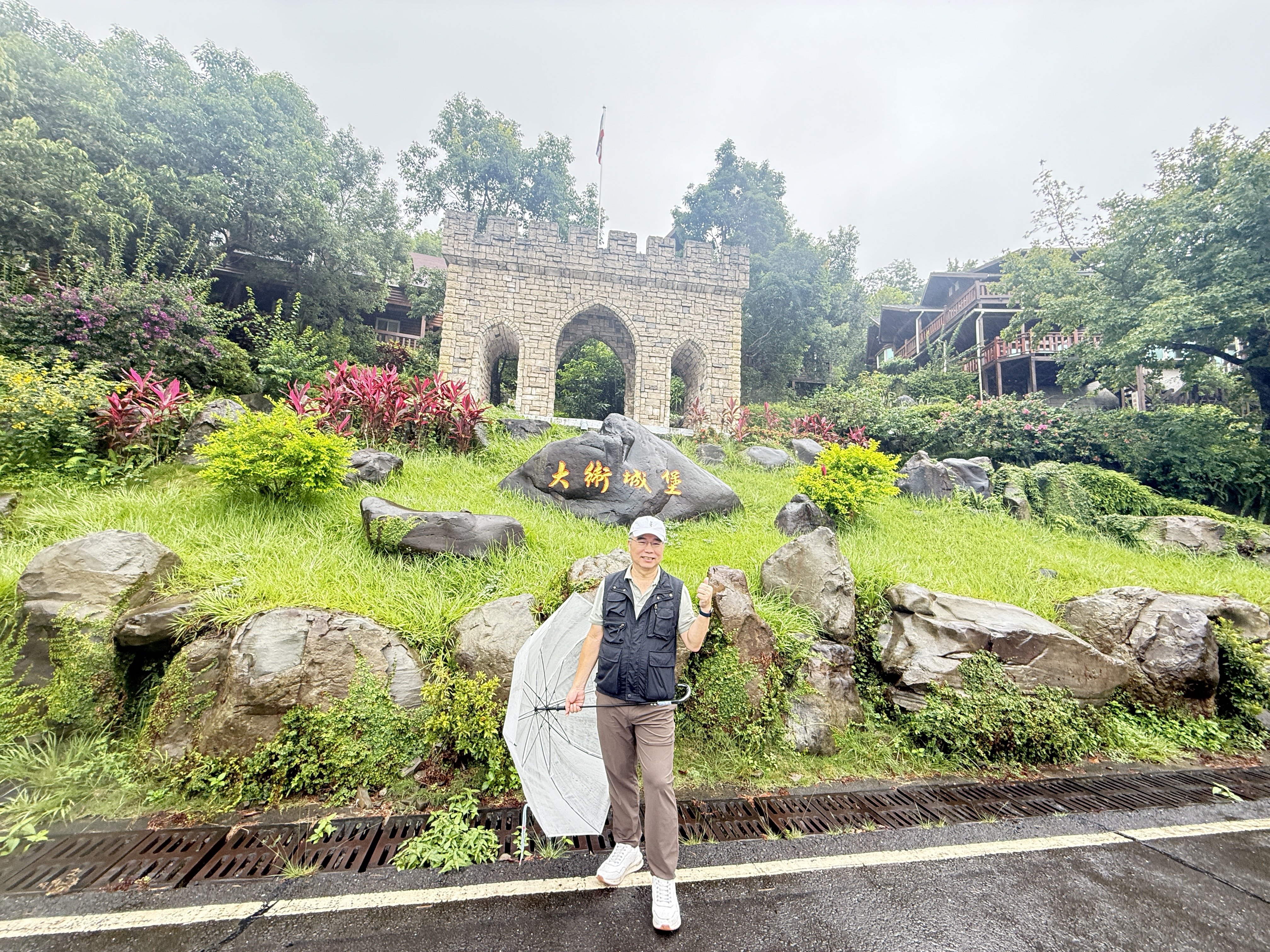 彰化錫安山區，遊客在綠意環繞的步道上散步，周圍有城堡式建築和山林背景。