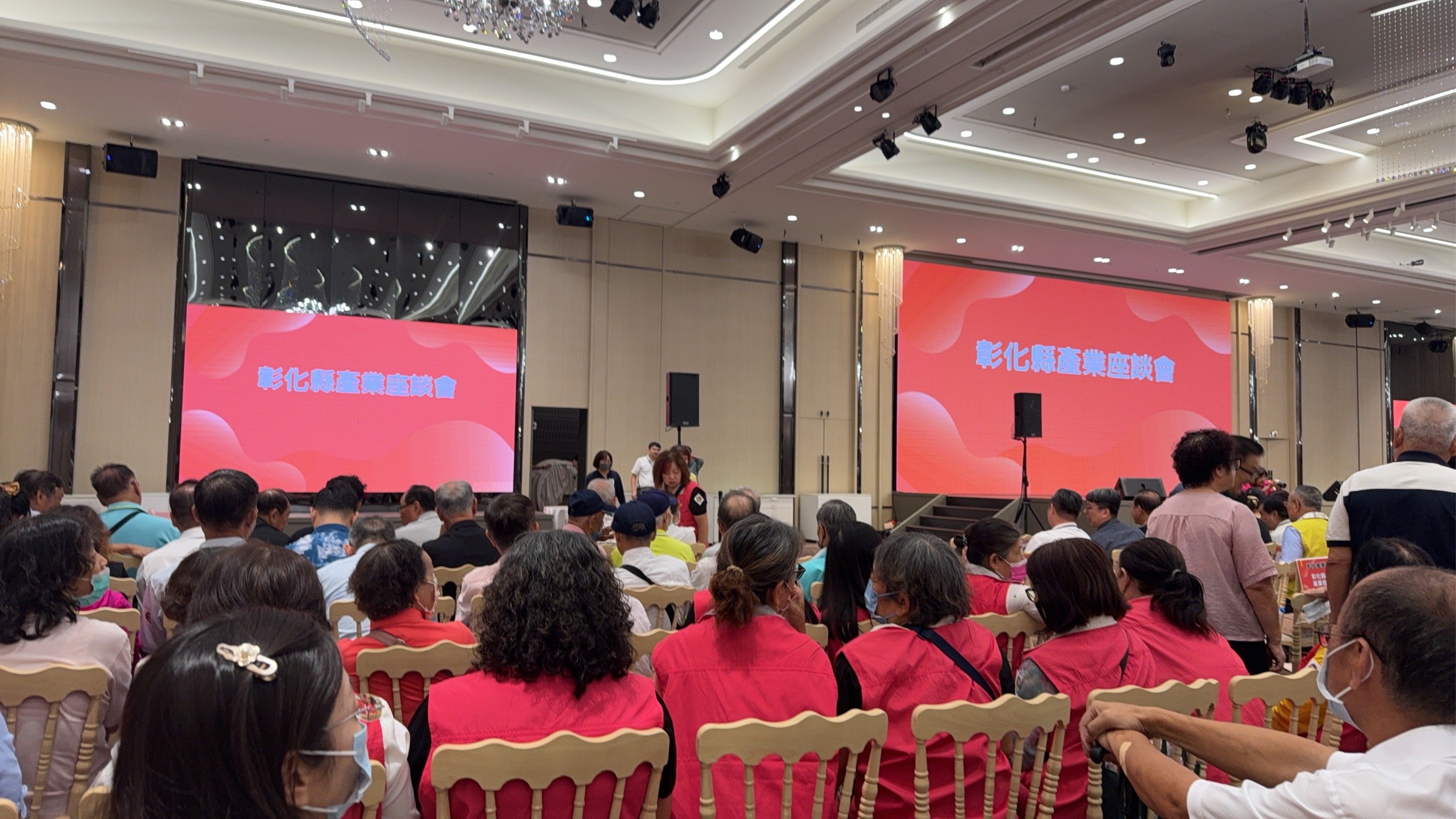 彰化縣傳統產業經濟座談會現場，講者在舞台發言，背景螢幕顯示智慧產業轉型相關關鍵字。