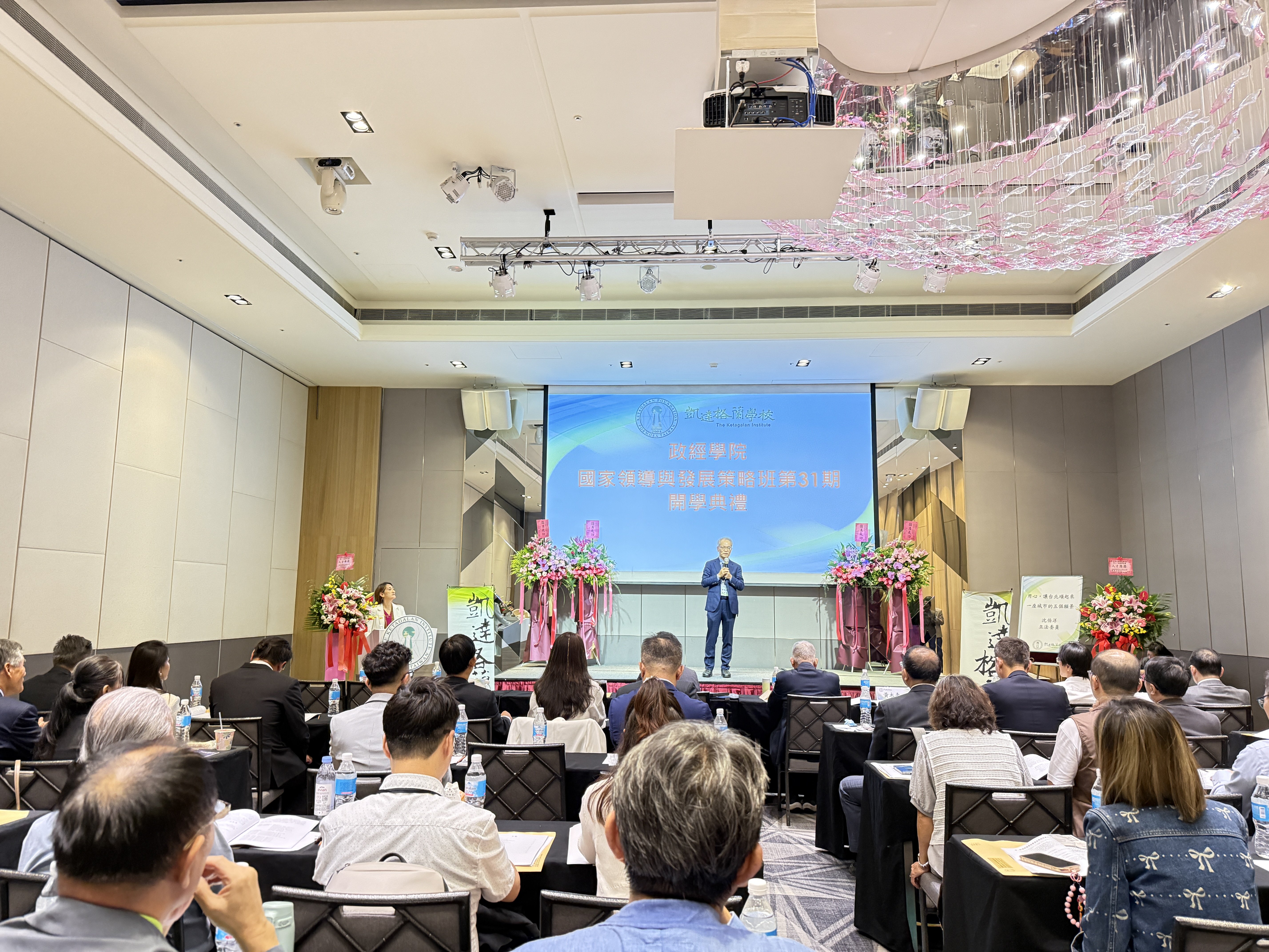 大學開學典禮或學術研討會現場，參與者聆聽講師報告與交流心得。