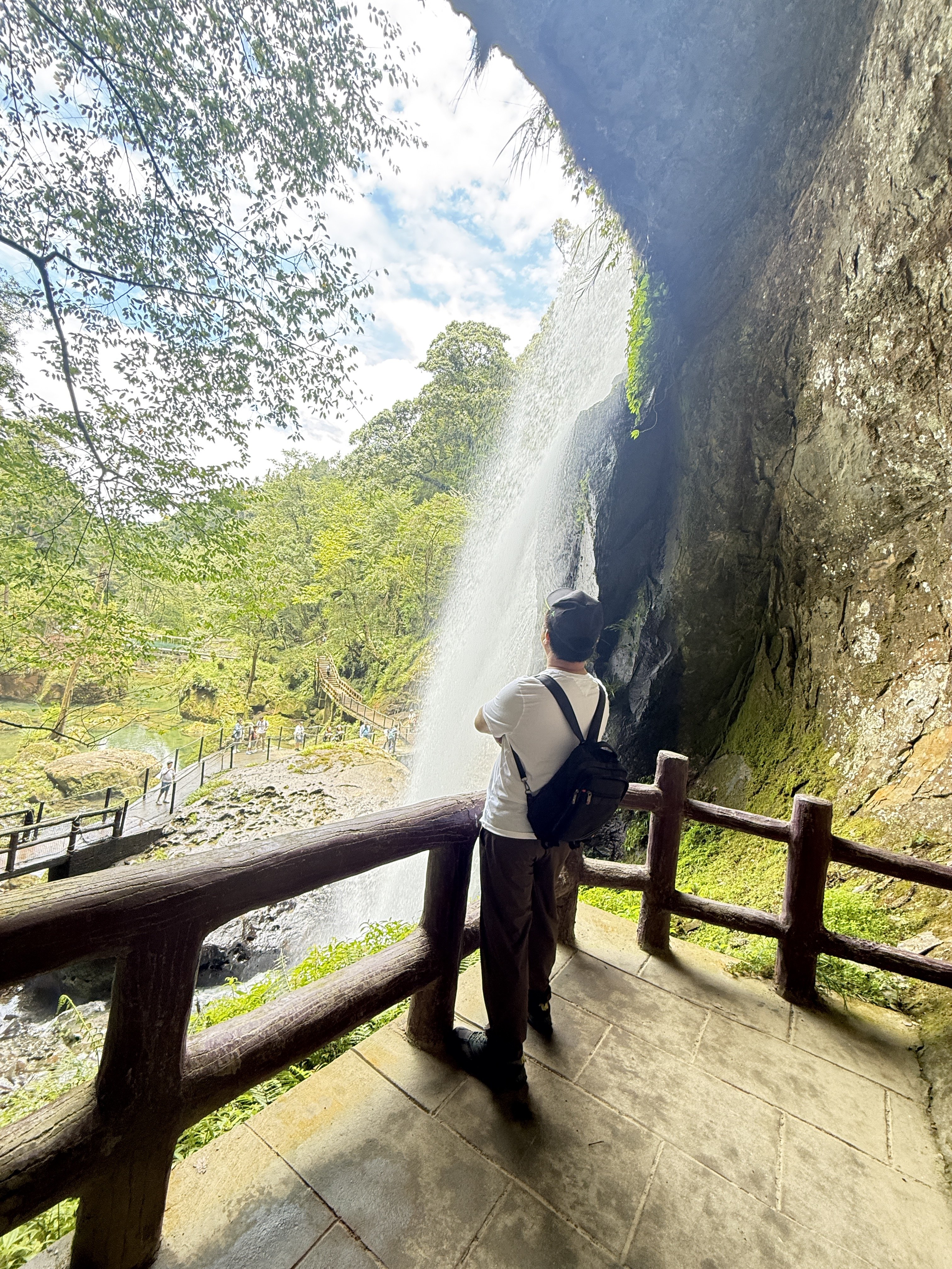 人在山林步道健走，周圍綠意盎然，有瀑布和森林背景。