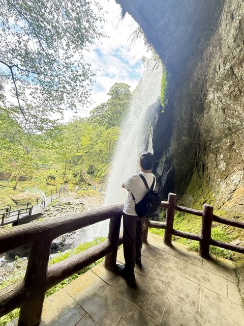 人在山林步道健走，周圍綠意盎然，有瀑布和森林背景。